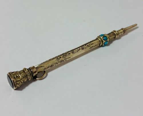 fig 2. An ornate Victorian gold propelling pencil featuring engraved floral motifs, set with round turquoise cabochons and fitted with a suspension ring.