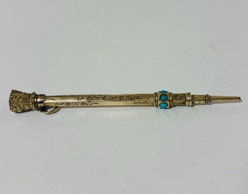 fig 3. An ornate Victorian gold propelling pencil featuring engraved floral motifs, set with round turquoise cabochons and fitted with a suspension ring.