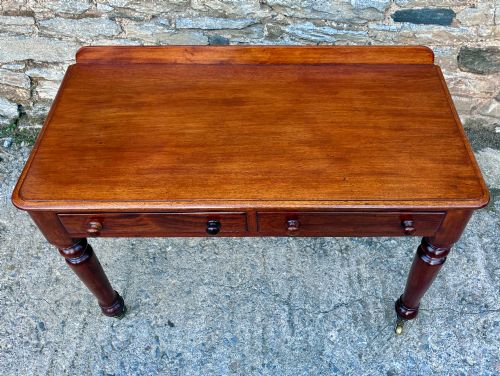 fig 1. A Victorian mahogany side table featuring a low rear gallery, two drawers with wooden knob handles, turned legs, and brass castors.