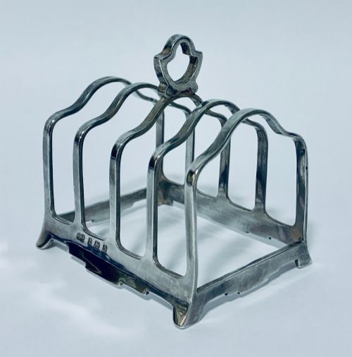 fig 1. A Victorian sterling silver toast rack featuring four arched dividers, a central loop handle, and stamped hallmarks along the front base rail.