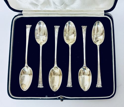 fig 1. A set of six silver teaspoons with decorative reeded handles displayed inside an open fitted presentation case lined in dark velvet and white satin.