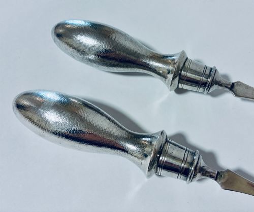 fig 2. A pair of antique silver salad servers displaying planished hammered handles and polished metal serving ends.