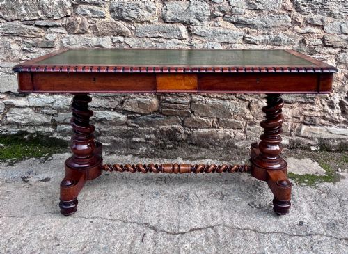 fig 1. A Victorian walnut library writing table featuring a green inset leather top, carved gadrooned edge, twin drawers, and spiral barley twist legs connected by a central stretcher.