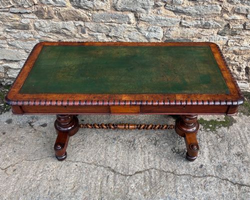 fig 2. A Victorian walnut library writing table featuring a green inset leather top, carved gadrooned edge, twin drawers, and spiral barley twist legs connected by a central stretcher.