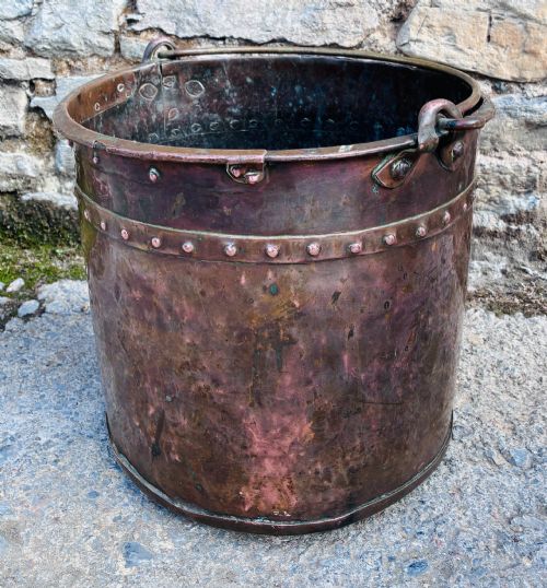 fig 1. An antique cylindrical copper bucket featuring heavy copper rivets along the upper rim band and a metal swing handle.