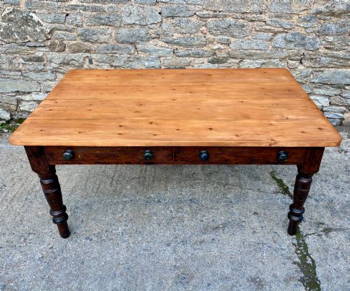 fig 1. A Victorian pine farmhouse table featuring a light natural timber plank top, two frieze drawers with round wooden knobs, and four dark turned wooden legs.
