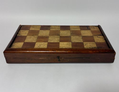 fig 1. An antique hinged wooden folding games board with a checkerboard surface, accompanied by turned draughts counters and a sliding wooden box containing chess pieces.