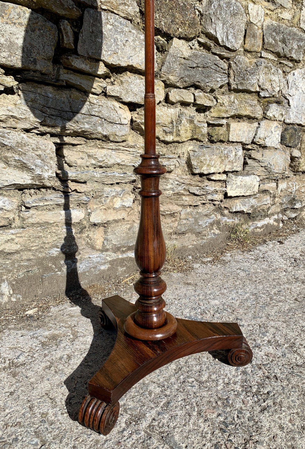 A Regency rosewood pole screen with a circular needlepoint panel on a turned column and triform base. View III