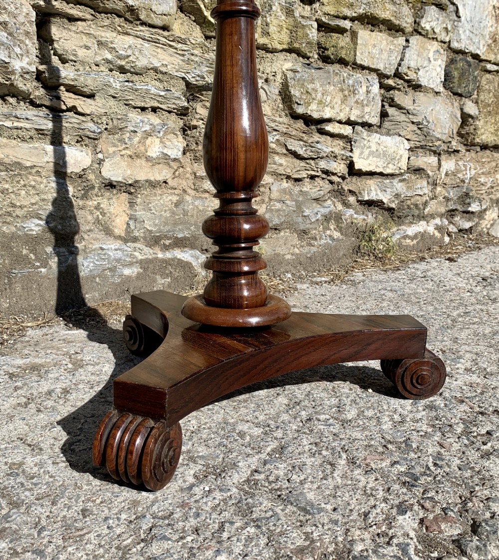 A Regency rosewood pole screen with a circular needlepoint panel on a turned column and triform base. View VI