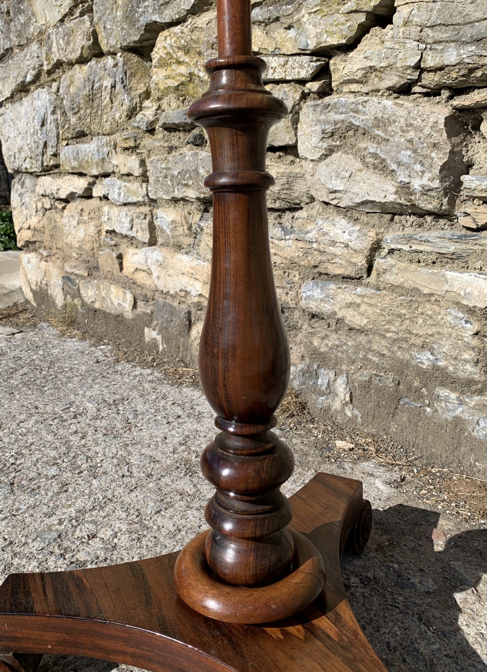 A Regency rosewood pole screen with a circular needlepoint panel on a turned column and triform base. View XII