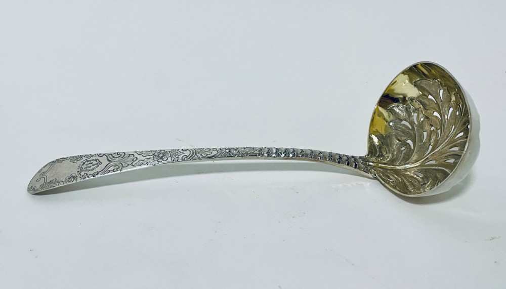 A Georgian sterling silver sugar sifter spoon featuring a hand-pierced foliate bowl design and an engraved floral handle. View III