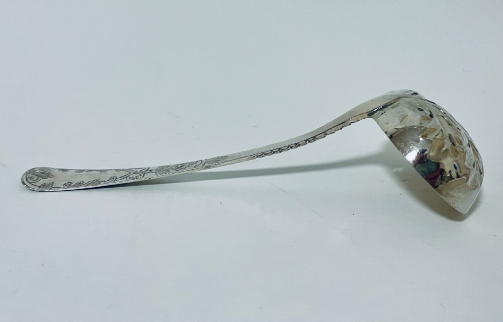 A Georgian sterling silver sugar sifter spoon featuring a hand-pierced foliate bowl design and an engraved floral handle. View IX