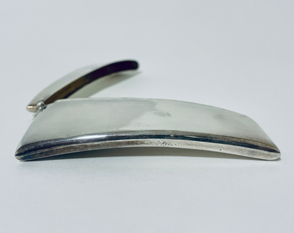A polished sterling silver rectangular calling card case featuring a gentle curve and visible British hallmarks near the upper rim. View X
