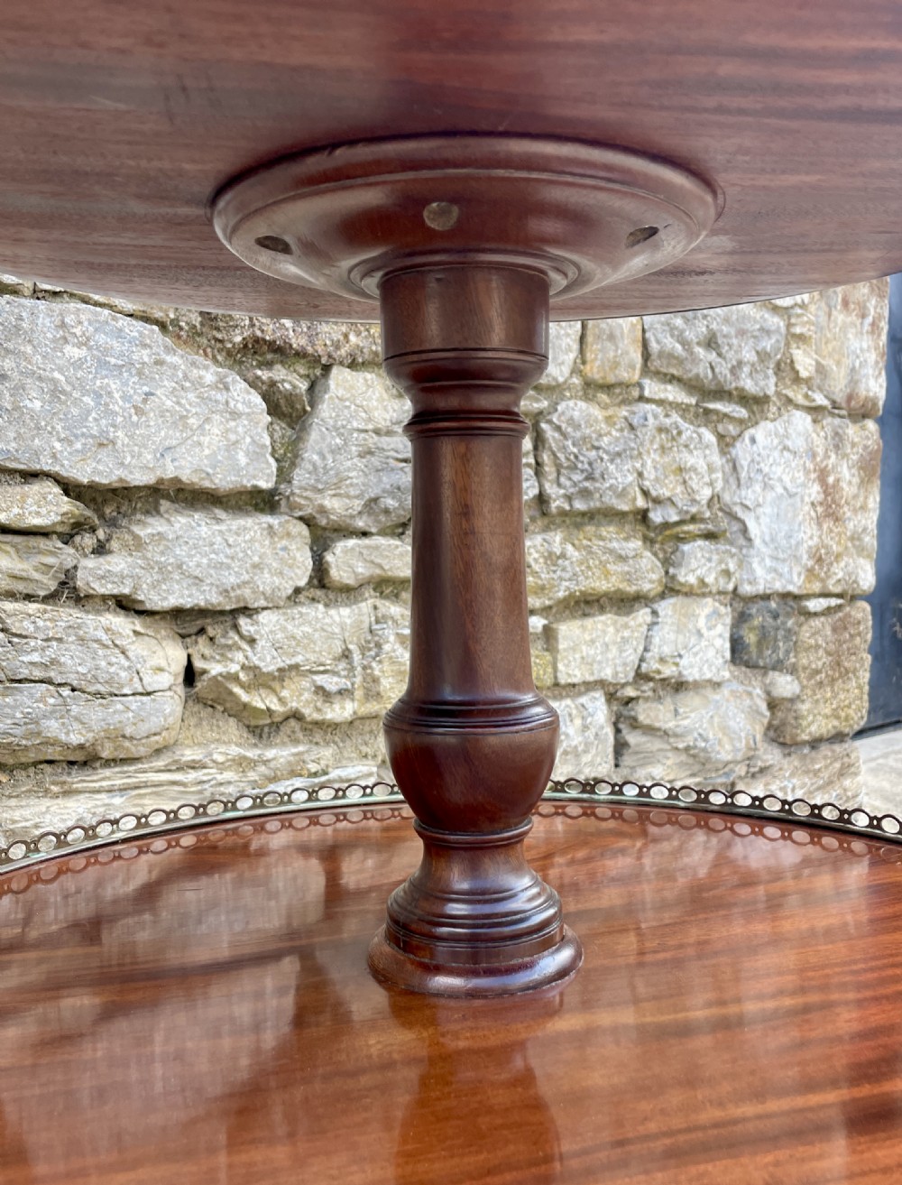 A Georgian dark mahogany two-tier dumb waiter featuring circular tops with pierced brass galleries, a central turned column, and sweeping reeded tripod legs on brass castors. View XVIII