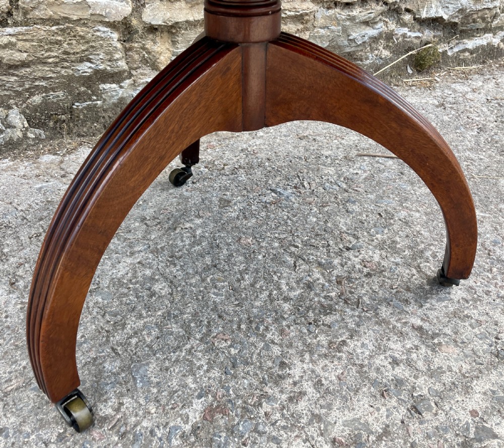 A Georgian dark mahogany two-tier dumb waiter featuring circular tops with pierced brass galleries, a central turned column, and sweeping reeded tripod legs on brass castors. View XXII