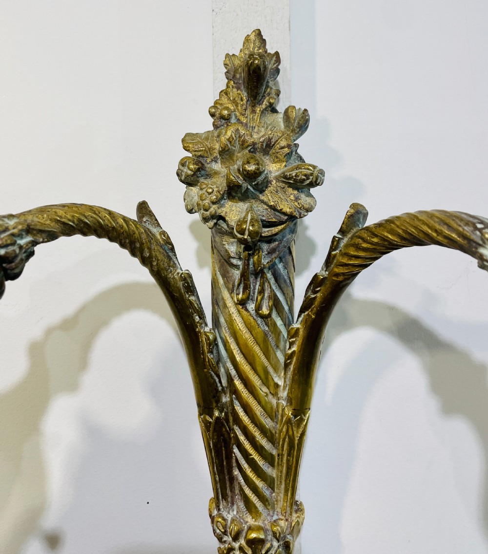 A Victorian twin-arm gilt brass wall sconce featuring reeded details, acanthus leaf motifs, and frosted frilled glass shades with etched floral patterns. View V