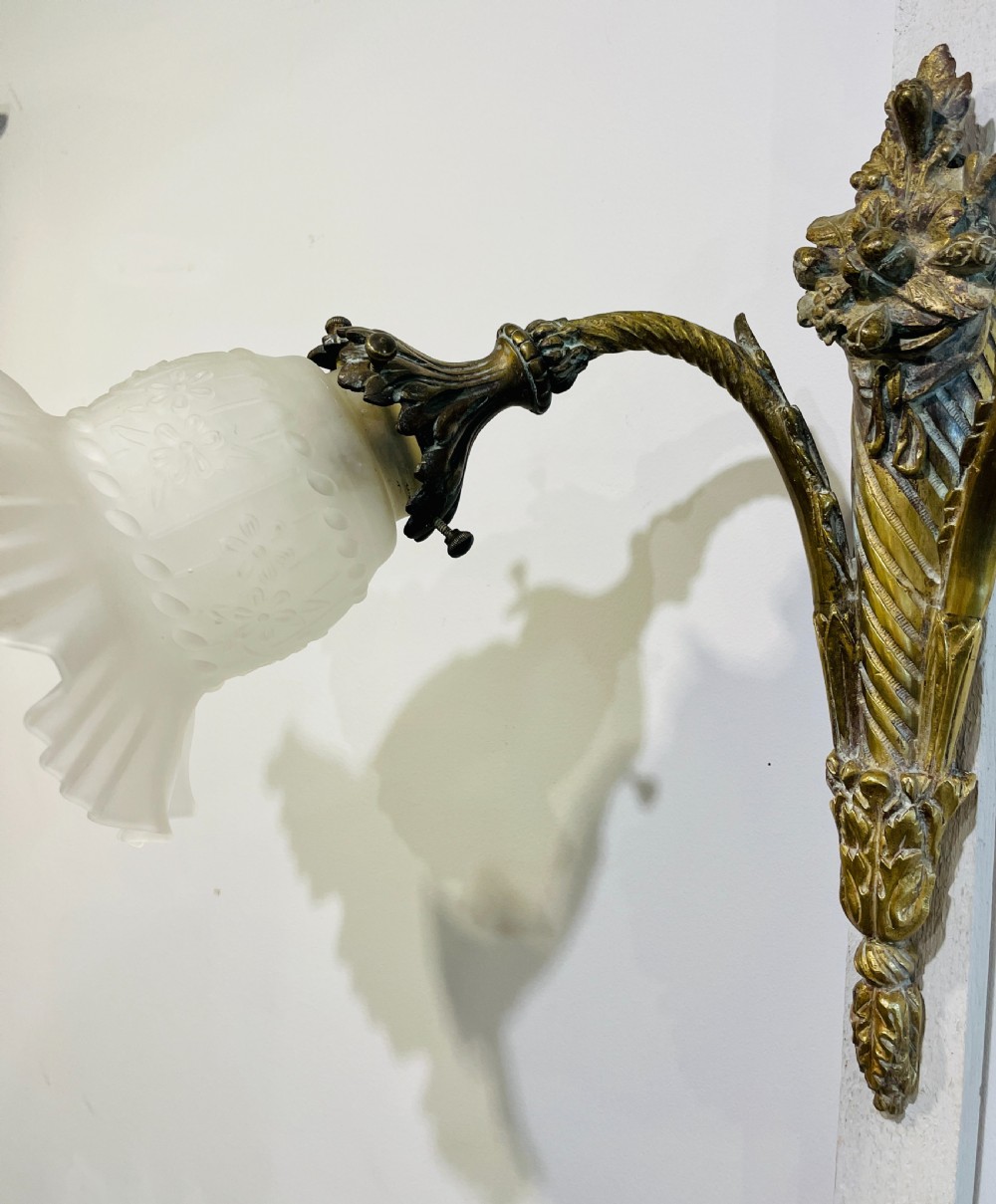 A Victorian twin-arm gilt brass wall sconce featuring reeded details, acanthus leaf motifs, and frosted frilled glass shades with etched floral patterns. View VII