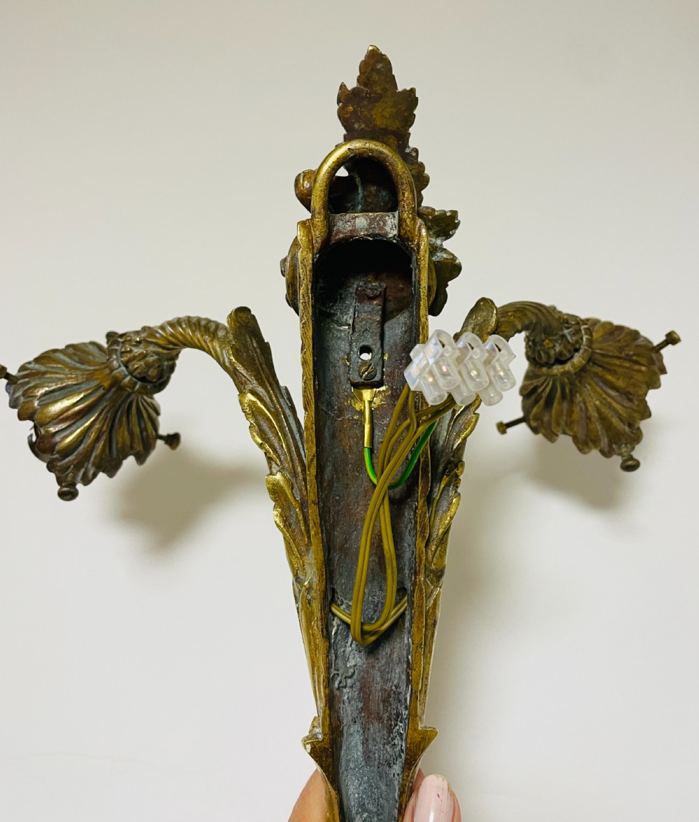 A Victorian twin-arm gilt brass wall sconce featuring reeded details, acanthus leaf motifs, and frosted frilled glass shades with etched floral patterns. View XV