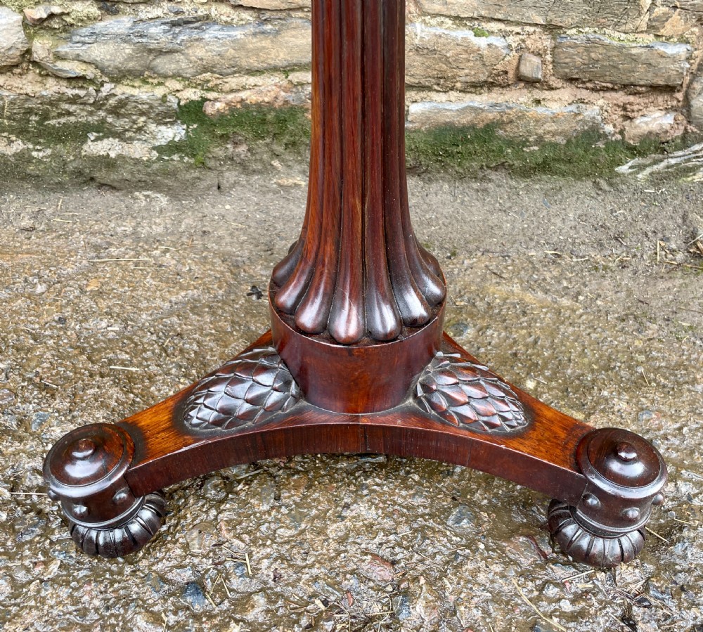 A Regency rosewood pole screen featuring a carved tripod base, adjustable brass rod, and a framed needlepoint panel with a floral wreath. View II