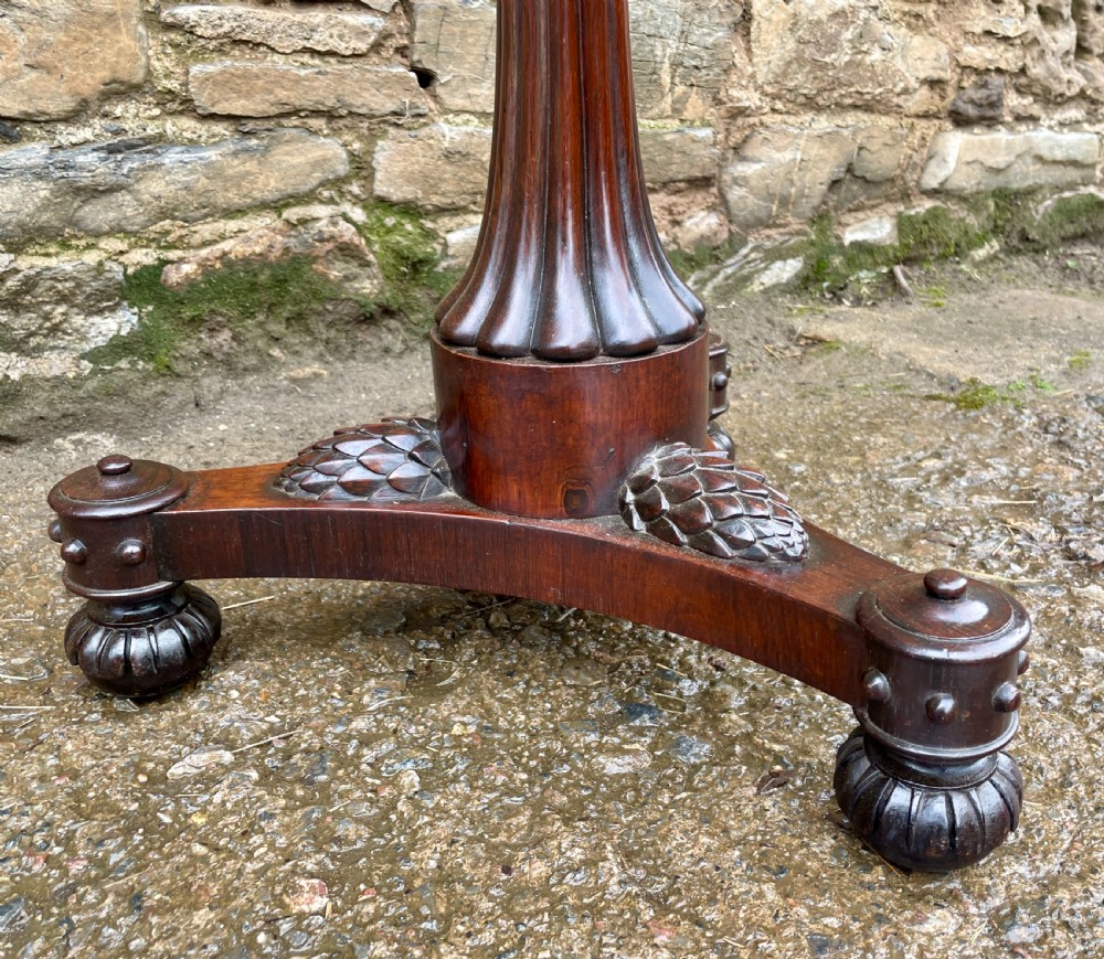 A Regency rosewood pole screen featuring a carved tripod base, adjustable brass rod, and a framed needlepoint panel with a floral wreath. View XIX