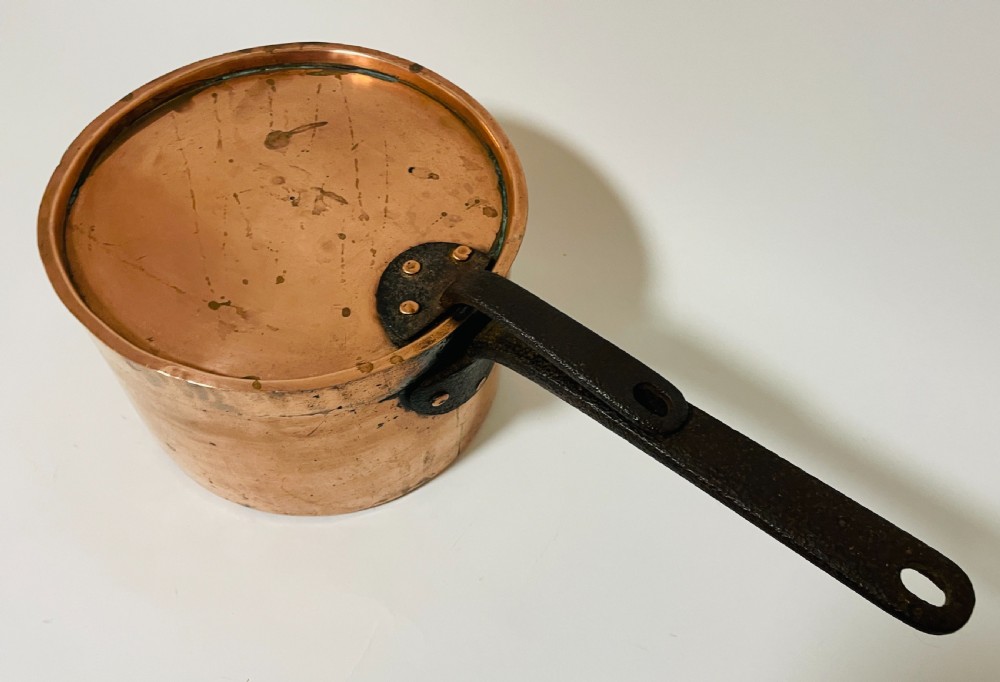 A large Victorian copper saucepan with a flat copper lid and a long dark cast iron handle. View II