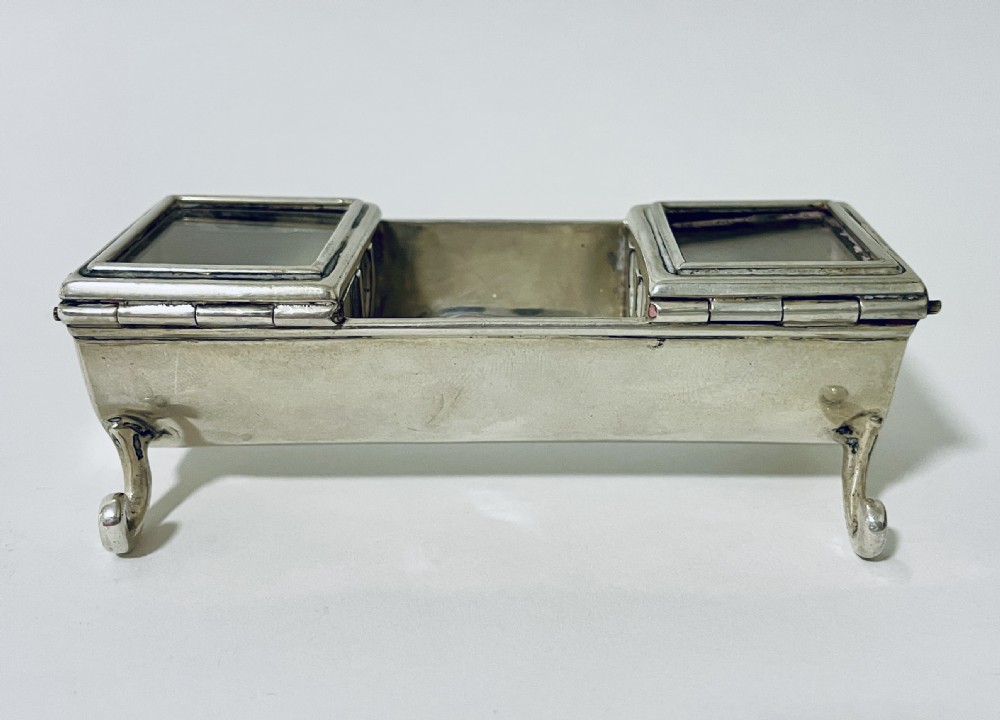 A rectangular Victorian silver double stamp trough with an engraved monogram, raised on four scrolled legs with two glass-topped compartments. View V