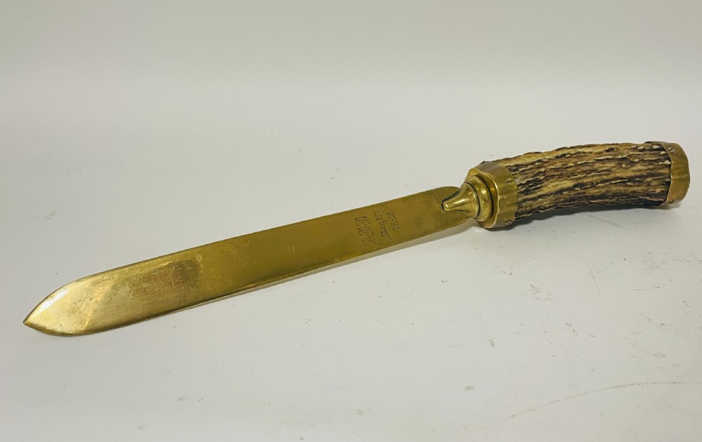 A Victorian desk set featuring a cut-glass inkwell in a brass frame, a brass letter opener with an antler handle, two small antler candlesticks, and a central brass-handled antler object. View IX