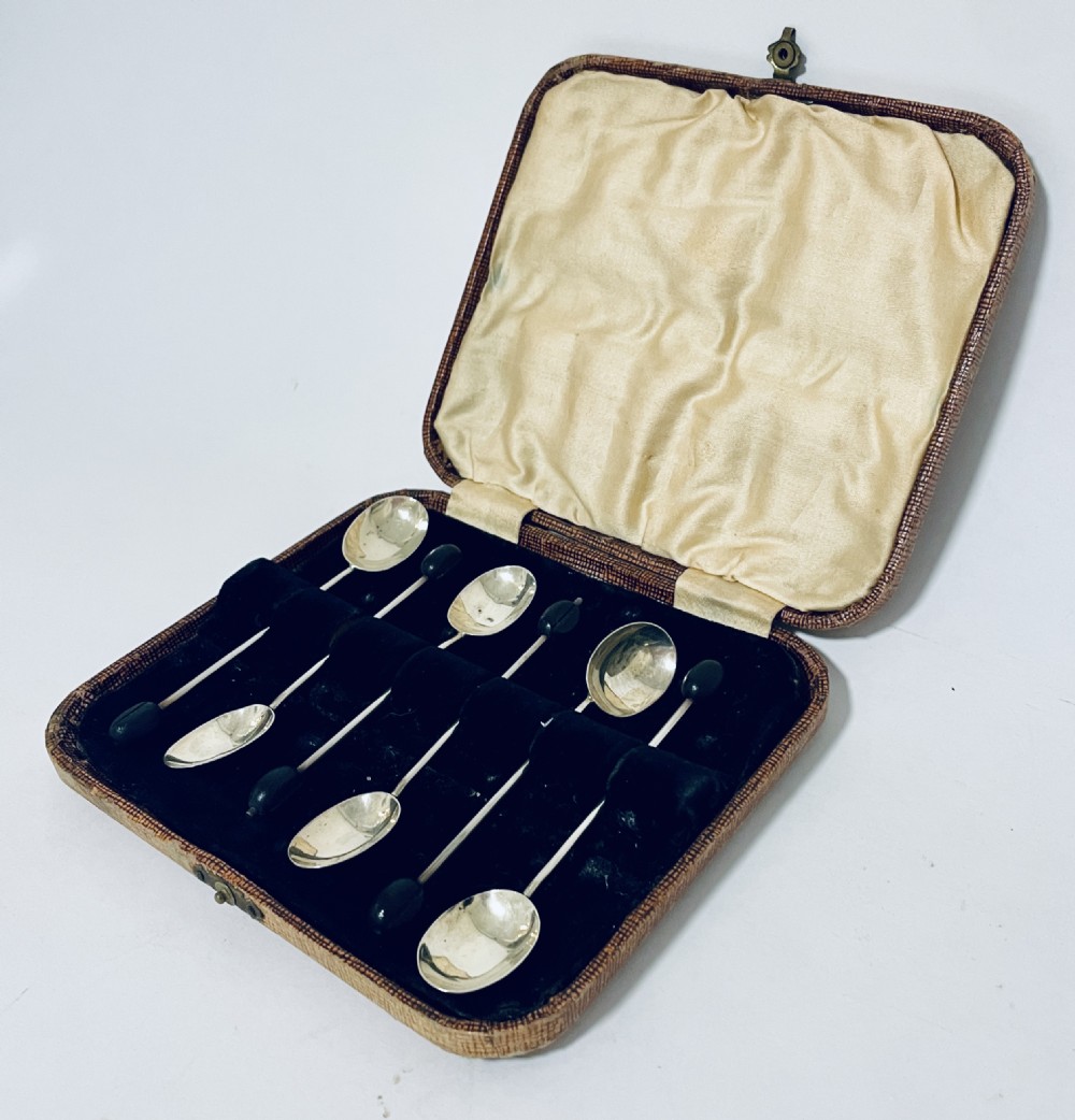 A set of six Art Deco silver coffee spoons with dark bean finials presented inside an open velvet-lined brown case. View III