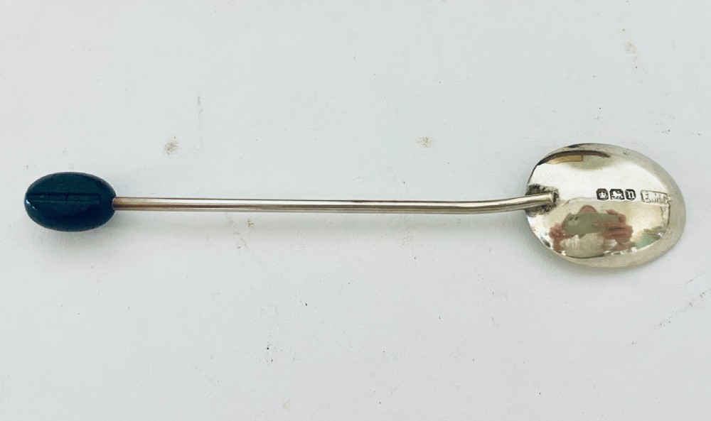 A set of six Art Deco silver coffee spoons with dark bean finials presented inside an open velvet-lined brown case. View V