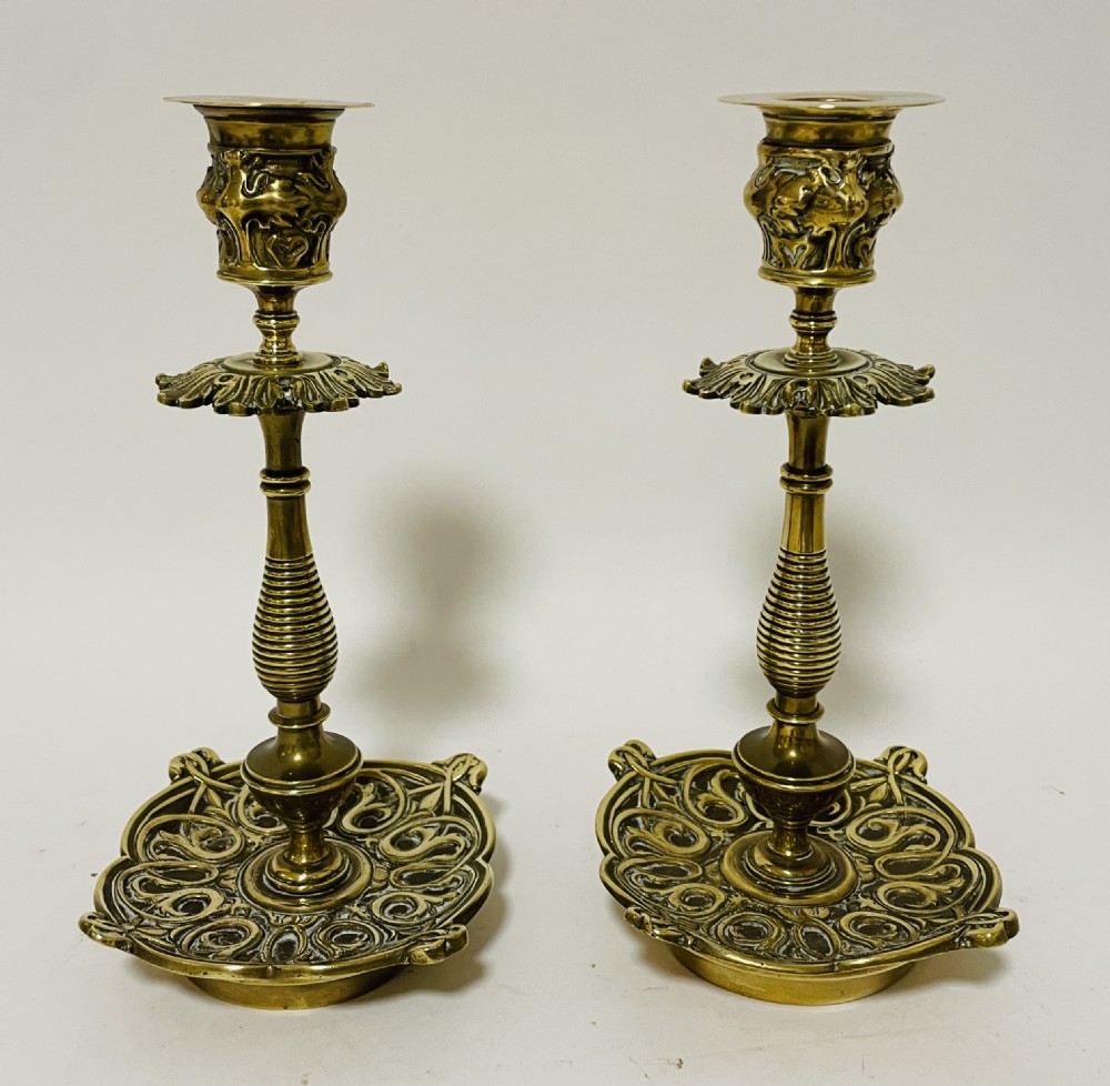 An ornate antique brass desk set featuring a lidded inkwell on a scrolled stand, a matching pen tray, and two turned brass candlesticks. View V