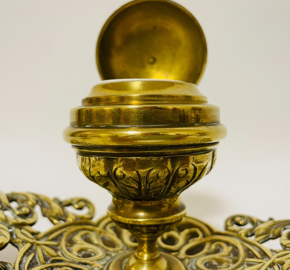 An ornate antique brass desk set featuring a lidded inkwell on a scrolled stand, a matching pen tray, and two turned brass candlesticks. View XIII