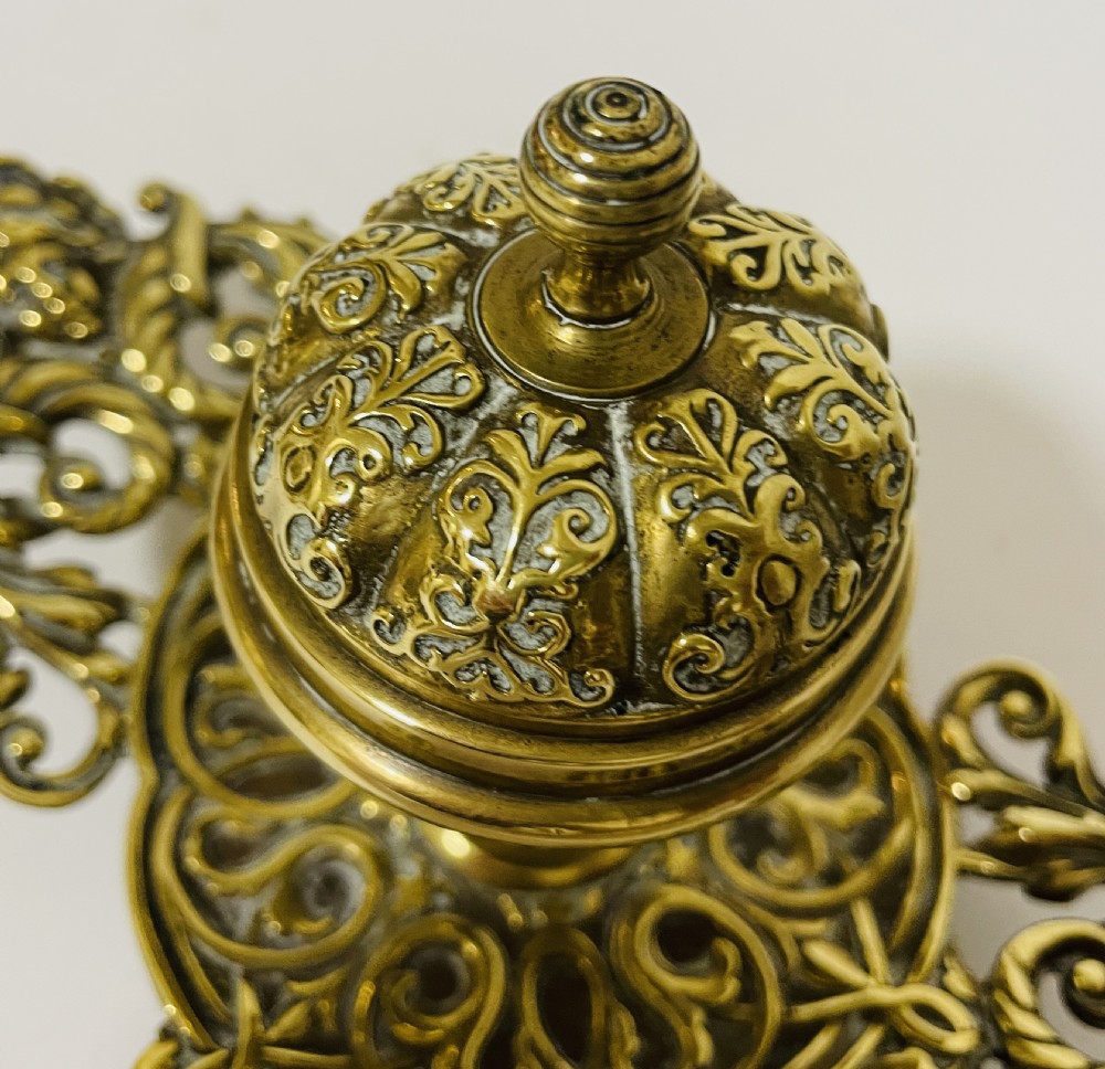An ornate antique brass desk set featuring a lidded inkwell on a scrolled stand, a matching pen tray, and two turned brass candlesticks. View XIV