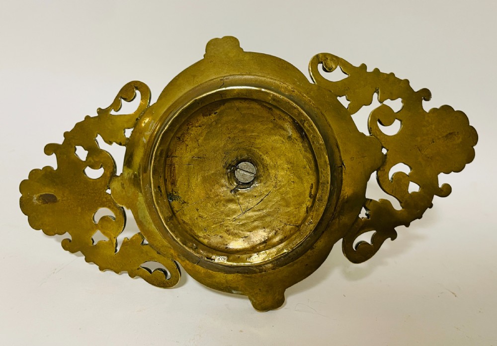 An ornate antique brass desk set featuring a lidded inkwell on a scrolled stand, a matching pen tray, and two turned brass candlesticks. View XV
