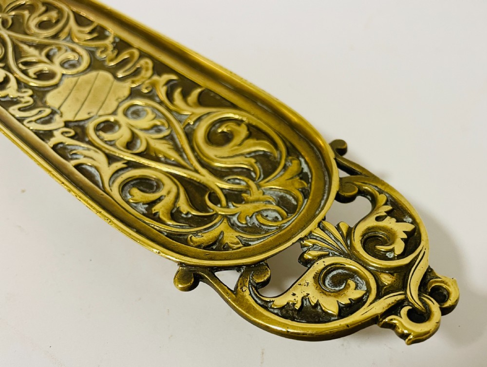 An ornate antique brass desk set featuring a lidded inkwell on a scrolled stand, a matching pen tray, and two turned brass candlesticks. View XVII