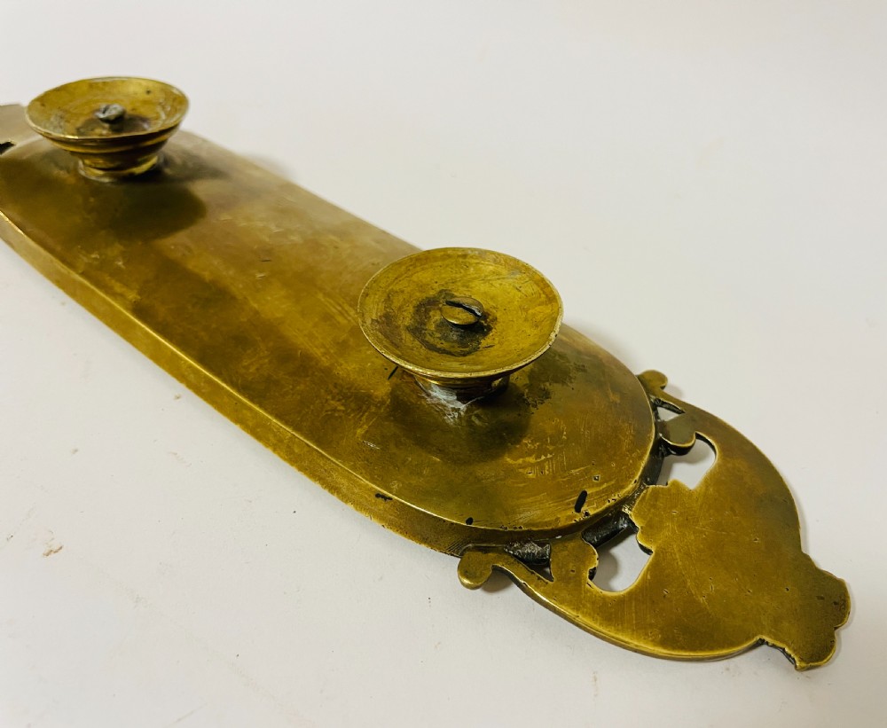 An ornate antique brass desk set featuring a lidded inkwell on a scrolled stand, a matching pen tray, and two turned brass candlesticks. View XX