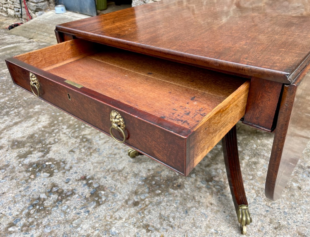 A Regency mahogany drop leaf pedestal table featuring reeded splayed legs, brass paw castors, and a drawer with lion mask handles. View III