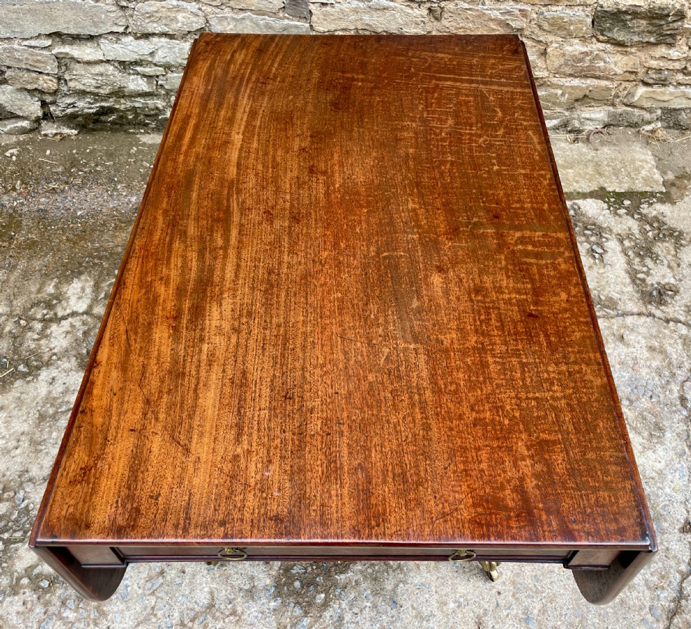 A Regency mahogany drop leaf pedestal table featuring reeded splayed legs, brass paw castors, and a drawer with lion mask handles. View VI