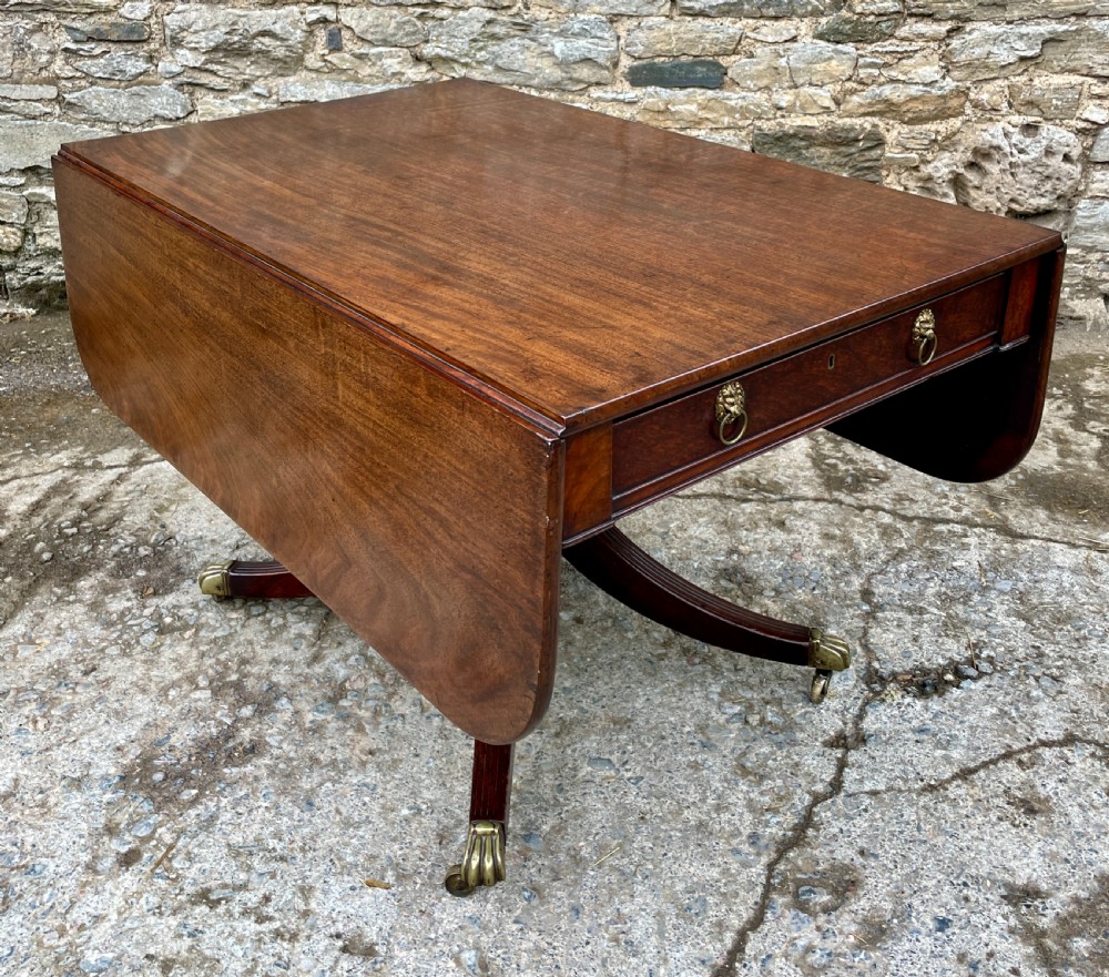 A Regency mahogany drop leaf pedestal table featuring reeded splayed legs, brass paw castors, and a drawer with lion mask handles. View XI