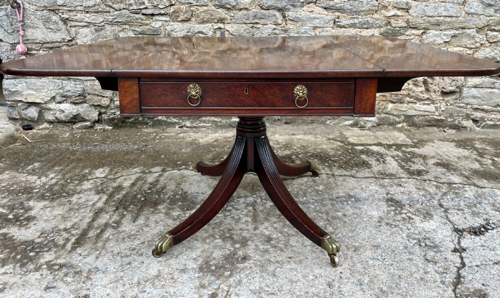 A Regency mahogany drop leaf pedestal table featuring reeded splayed legs, brass paw castors, and a drawer with lion mask handles. View XIII