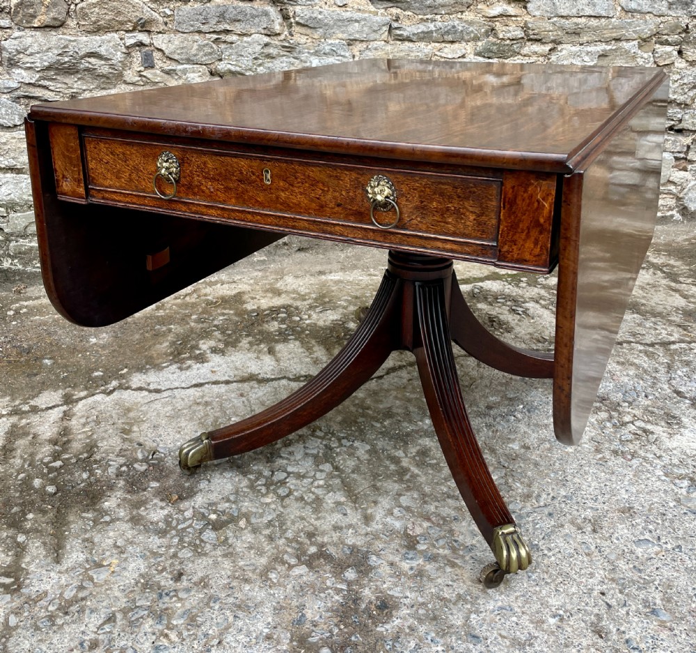 A Regency mahogany drop leaf pedestal table featuring reeded splayed legs, brass paw castors, and a drawer with lion mask handles. View XVII
