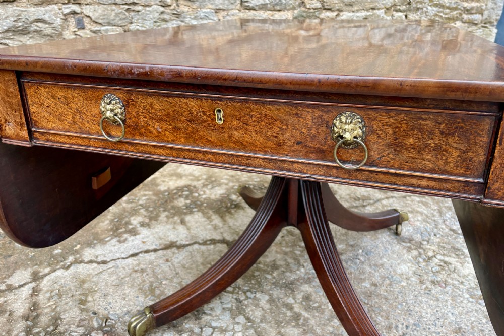 A Regency mahogany drop leaf pedestal table featuring reeded splayed legs, brass paw castors, and a drawer with lion mask handles. View XVIII