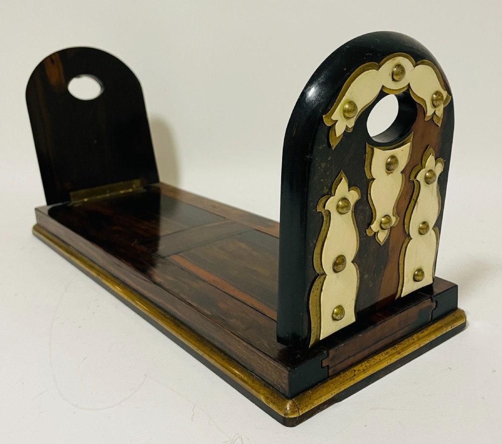An antique Victorian coromandel wood expanding book slide featuring brass trim and decorative bone mounts pinned with studs.
