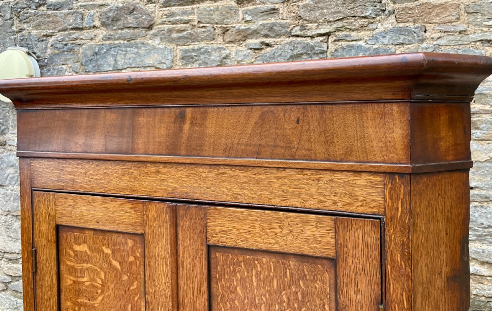 A floor-standing Georgian oak corner cupboard featuring double panelled doors and a moulded top cornice. View X