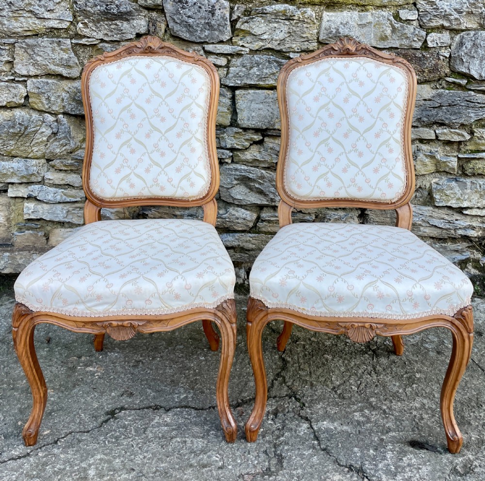 A pair of carved walnut French salon chairs featuring patterned cream upholstery, shell crest carvings, and cabriole legs. View II