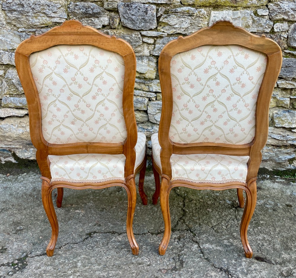 A pair of carved walnut French salon chairs featuring patterned cream upholstery, shell crest carvings, and cabriole legs. View III