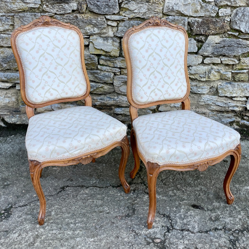 A pair of carved walnut French salon chairs featuring patterned cream upholstery, shell crest carvings, and cabriole legs. View VIII