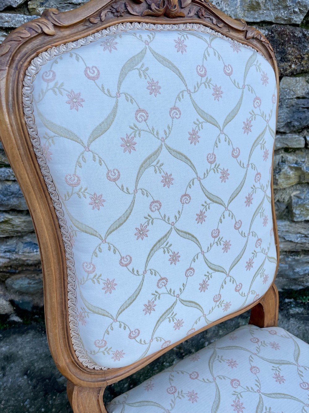 A pair of carved walnut French salon chairs featuring patterned cream upholstery, shell crest carvings, and cabriole legs. View IX