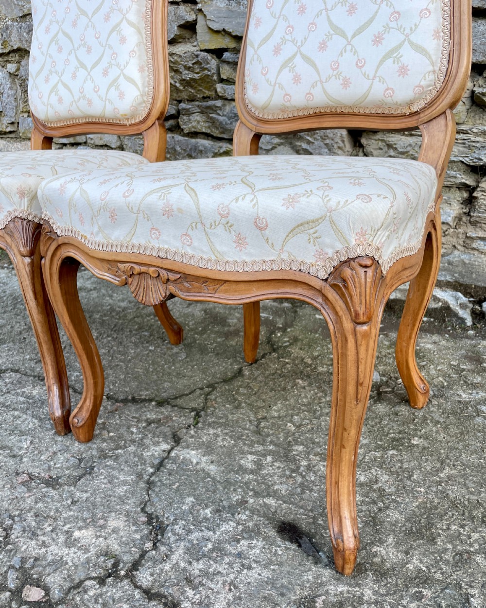 A pair of carved walnut French salon chairs featuring patterned cream upholstery, shell crest carvings, and cabriole legs. View XI