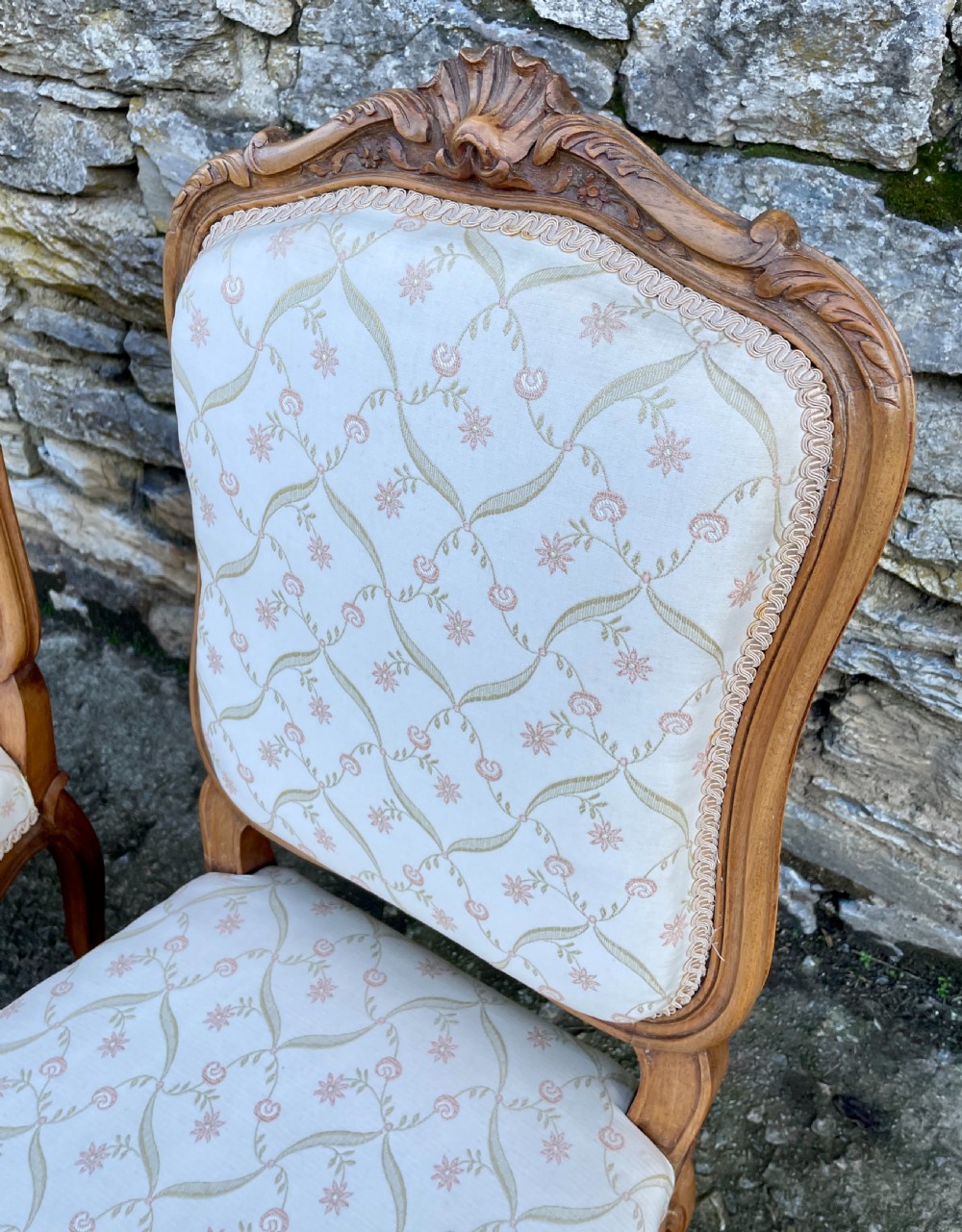 A pair of carved walnut French salon chairs featuring patterned cream upholstery, shell crest carvings, and cabriole legs. View XIV