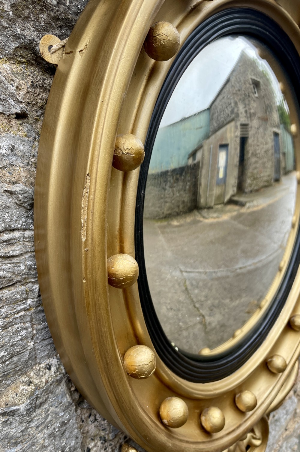 An ornate circular giltwood convex mirror featuring a carved eagle top cresting, acanthus leaf scrolling, ball mouldings, and an ebonised inner slip frame. View III